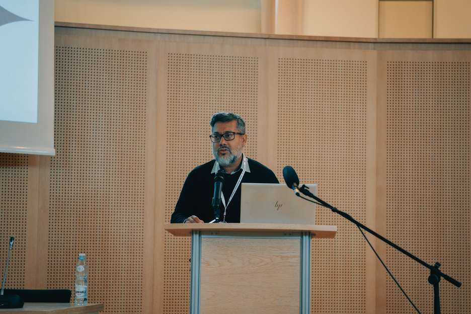 OU Shafquat Towheed standing at the podium delivering his keynote on the Future of Reading